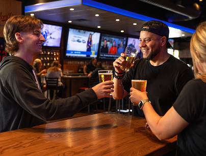 Smiling customers toasting and enjoying cold draft beers at Glory Days Grill